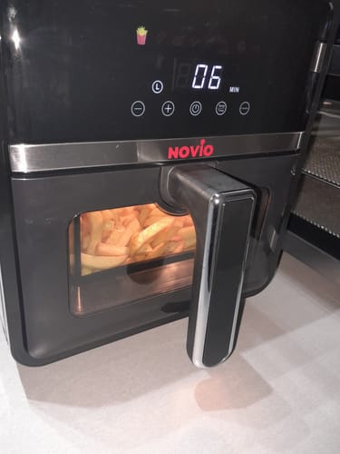 Clientul gătește cartofi prăjiți în friteuza Air Fryer Novio StonePro; afișajul digital arată 6 minute.