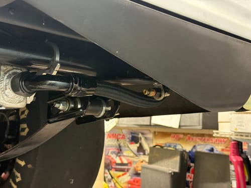 Customer's remote drain kit installed under a vehicle, with the black line and bulkhead fitting visible.