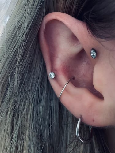 Customer wearing the Solitaire flatback Silver stud in a cartilage piercing, among other earrings.