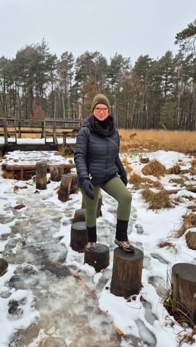 Kundin posiert in ihrer olivgrünen Tofana Leggings in einer winterlichen Landschaft.