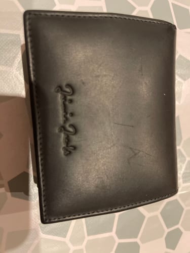Customer's closed black Flap Boy XL wallet showing some light scratches on the smooth leather.