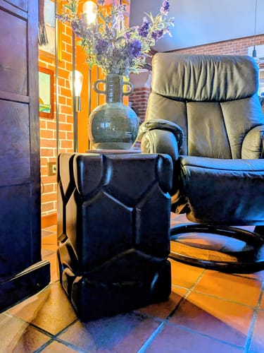 Klant toont het donkere Brooklyn krukje als bijzettafel in een woonkamer, met een vaas erop.