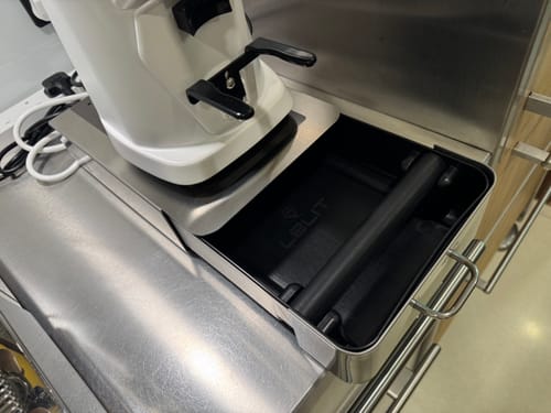 Reviewer's LELIT Rectangular Knock Box with its drawer pulled out, placed under a coffee grinder on a stainless steel counter.