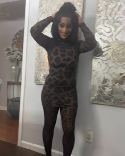 Customer posing with hands in her hair while wearing the leopard print Naked Print Mini Dress.