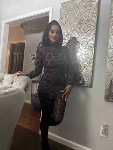Reviewer leaning against a wall indoors while wearing the long-sleeved Naked Print Mini Dress.