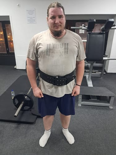 Reviewer standing in a gym wearing the all-black 13MM Double Prong Belt around their waist.