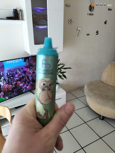 Ein Kunde hält den RANDM TORNADO 15000 Vape in der Hand und zeigt das grüne Gerät mit der Affen-Grafik.