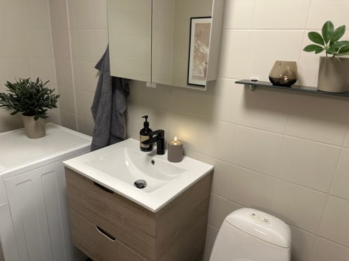 Kundes baderomsskap dekket med lys Oak minimal kontaktplast ved siden av en vaskemaskin.