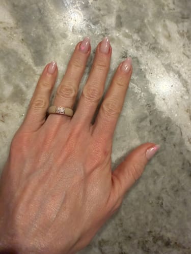 Customer's hand wearing the nude silicone ring with a sparkling stone setting on the ring finger.