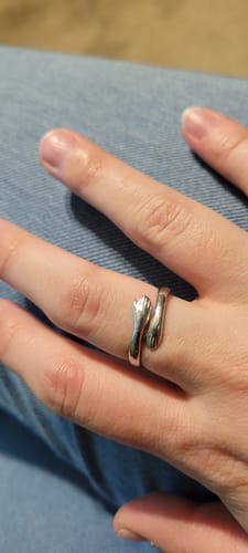 Customer wearing the silver Hug From Heaven Ring on their finger, showing its design of two hands in a loving hug.