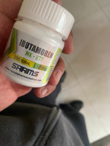Un cliente sostiene en su mano el frasco blanco de Ibutamoren MK-677, mostrando la etiqueta del producto.