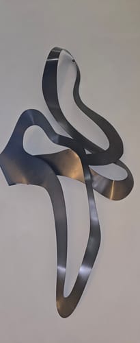 Customer's black Hand Crafted Stainless Steel Artwork with an abstract, flowing design mounted on a wall.