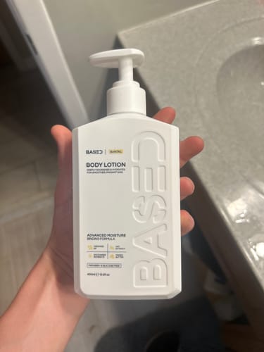 Customer holding the white bottle of Based Santal Body Lotion.