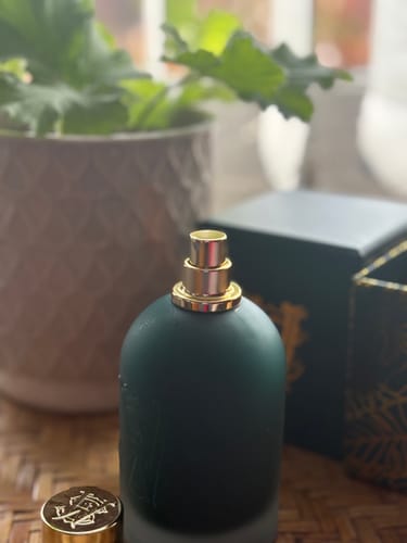 A reviewer's dark green Rose Boheme perfume bottle, shown uncapped with the gold lid beside it.