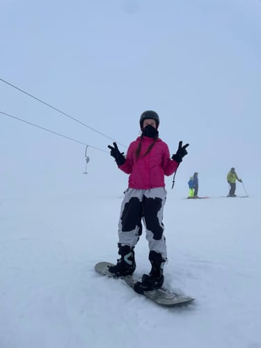 Customer wearing the baggy off white snow pants while standing on a snowboard on a foggy slope.