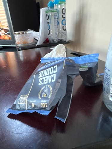 Customer's empty and torn wrapper for a Cael's Cookie, shown on a desk.