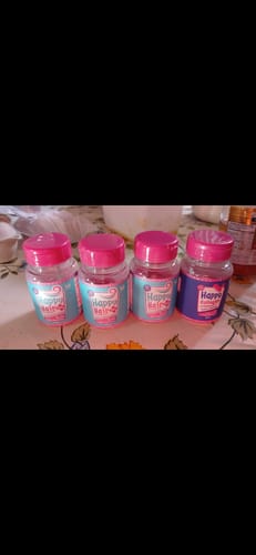 Cliente exibe três potes de Happy Hair e um de Happy Collagen do kit, alinhados sobre uma superfície.