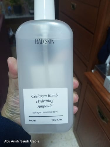 Reviewer holds the large 400ml bottle of Bad Skin Korean Collagen Bomb Hydrating Ampoule.