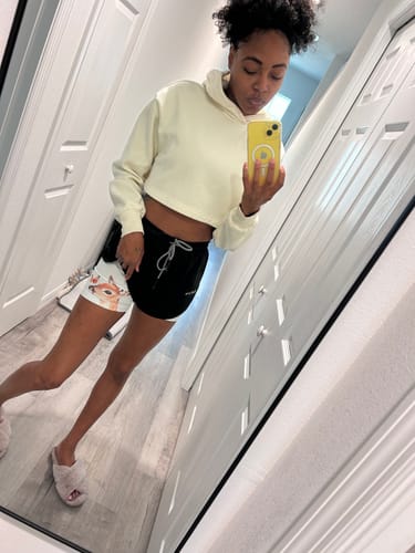 Customer taking a mirror selfie in a hallway wearing the black 'Peaceful Trust' Girls Performance Shorts.