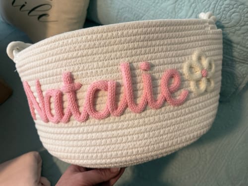 Customer holding a personalized white woven basket with the name 'Natalie' in pink script.