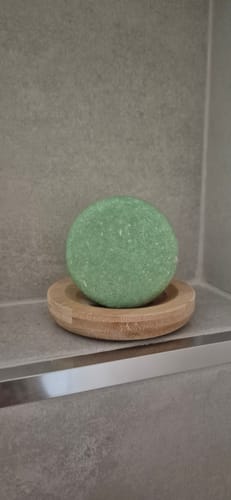 Customer's green Peppermint Shampoo Bar on a bamboo drainer dish in a tiled shower.
