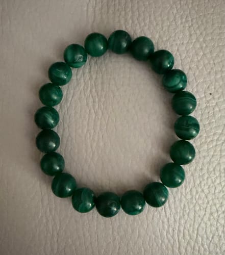 Photo d'un client du bracelet en perles de Malachite de 10 mm, posé à plat sur une surface claire.