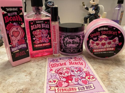 Reviewer displays the pink bath products from the February Monthly Subscription Box on a counter.