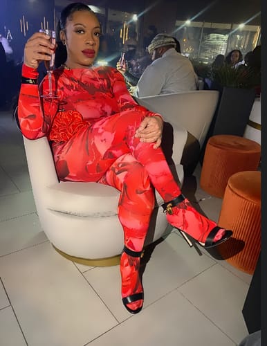 Customer sitting in a chair at a lounge wearing the red Bare Body Print Closed Toe Leggings.