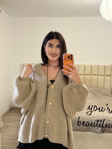 Kundin zeigt den lockeren, beigen Oversized Cardigan 'CozyGlam' in einem Spiegelselfie.