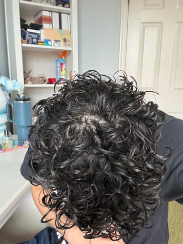A reviewer's dark hair seen from above, showing defined, shiny curls after using the Curly Duo.