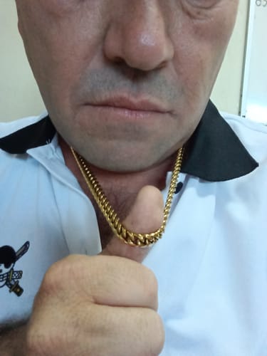 Primer plano de un cliente que lleva la Cadena Cuban Link Oro de 8mm alrededor del cuello, haciendo un gesto de aprobación.