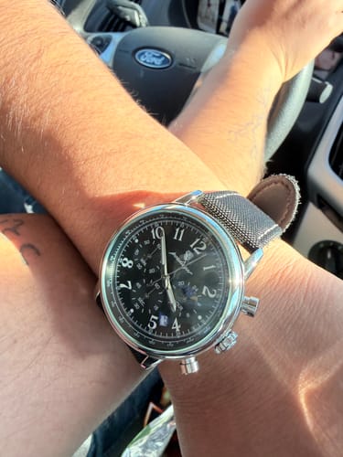 Customer's wrist with the Lucky Fours® Shoreline watch, showing the black chronograph face and silver case in a car.