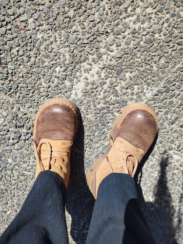 Customer's top-down view of the colorblock leather platform Martin boots on a gravel path.