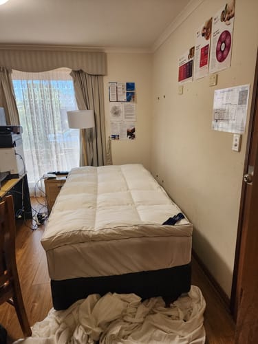 Reviewer's Muscle Mat Mattress Topper looking plush and thick on a single bed in a bedroom.