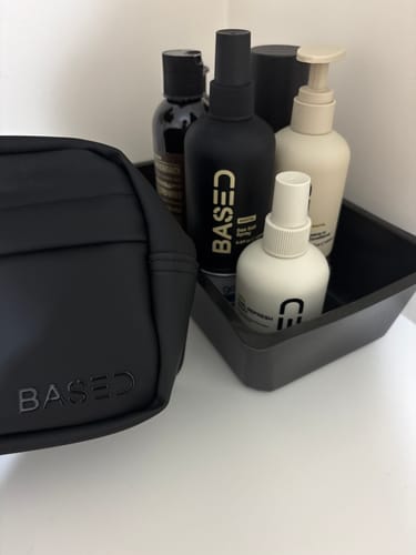 Customer's Sea Salt Spray in a black bottle, organized in a tray with other toiletries and a matching bag.