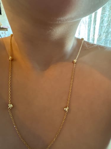 Customer wearing the Jane Heart Station Necklace with its small, gold-colored hearts.