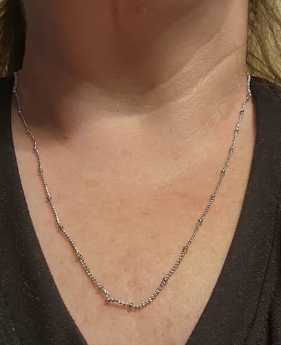 Reviewer wearing the delicate Pria bead station chain necklace against a black top.