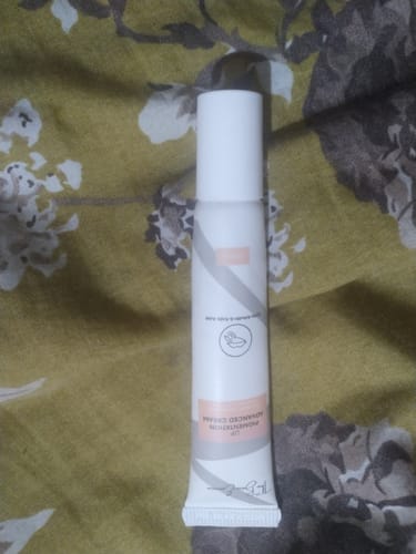 Customer's white tube of Advance Lip Pigmentation Cream resting on a floral patterned fabric.