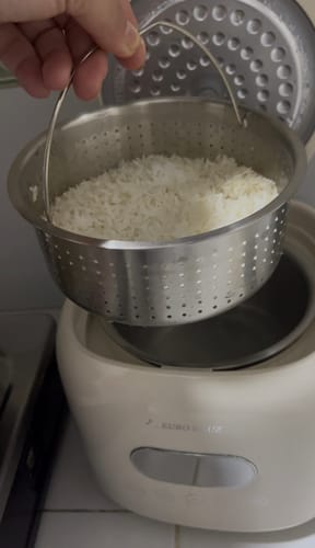 A customer lifts the perforated inner pot with cooked rice from the cream-colored Eurohauz Healthy Rice Cooker.