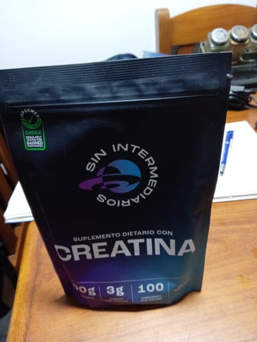 El cliente muestra una bolsa negra de suplemento de Creatina de la marca Sin Intermediarios sobre una mesa.