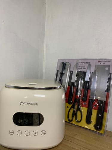 Customer's cream-colored Eurohauz Healthy Rice Cooker on a surface next to the free, packaged knife set.