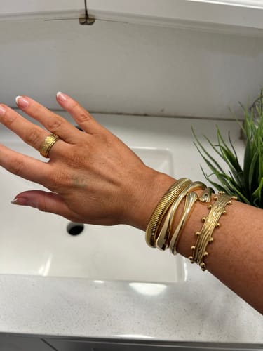 Reviewer's wrist with the Tidebreak Cuff bundle worn as a stylish gold stack.