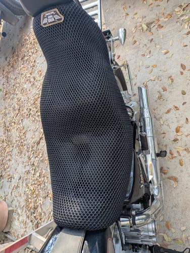 Customer's black mesh Wind Rider Seat Cover fitted onto a motorcycle, viewed from an overhead angle outdoors.