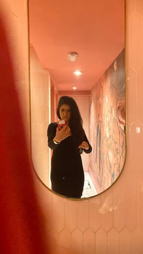 Reviewer taking a mirror selfie in a black Long Sleeve Midi Shapewear Dress in a pink hallway.