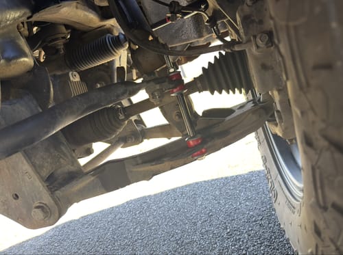 Customer's installed red KSP front sway bar link shown on their vehicle's undercarriage.