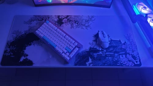 Customer's Ink Blossom desk pad with a keyboard and mouse on top, set on a desk with blue lighting.