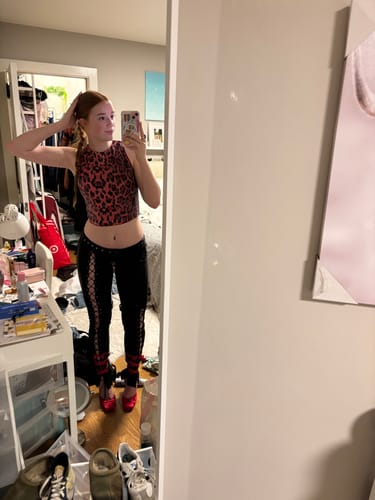 Reviewer in a mirror selfie wearing the black Vice Pant with a red top, showing the low-rise fit and side lace-up detail.