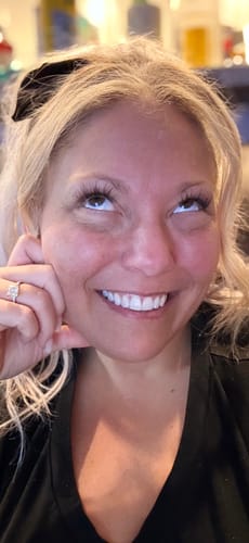 Customer looks up smiling, showing her long, full lashes after nine days of wear.