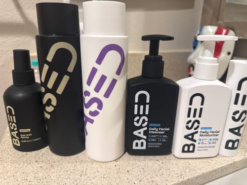 Customer's collection of Based Bodyworks products, including the Shower Duo shampoo and conditioner, on a bathroom counter.