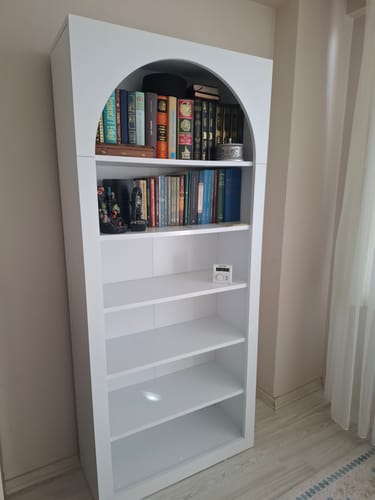 Müşterinin odasına kurduğu beyaz, kemerli tasarımlı Rani kitaplık. Üst raflar dolu, alt raflar boştur.